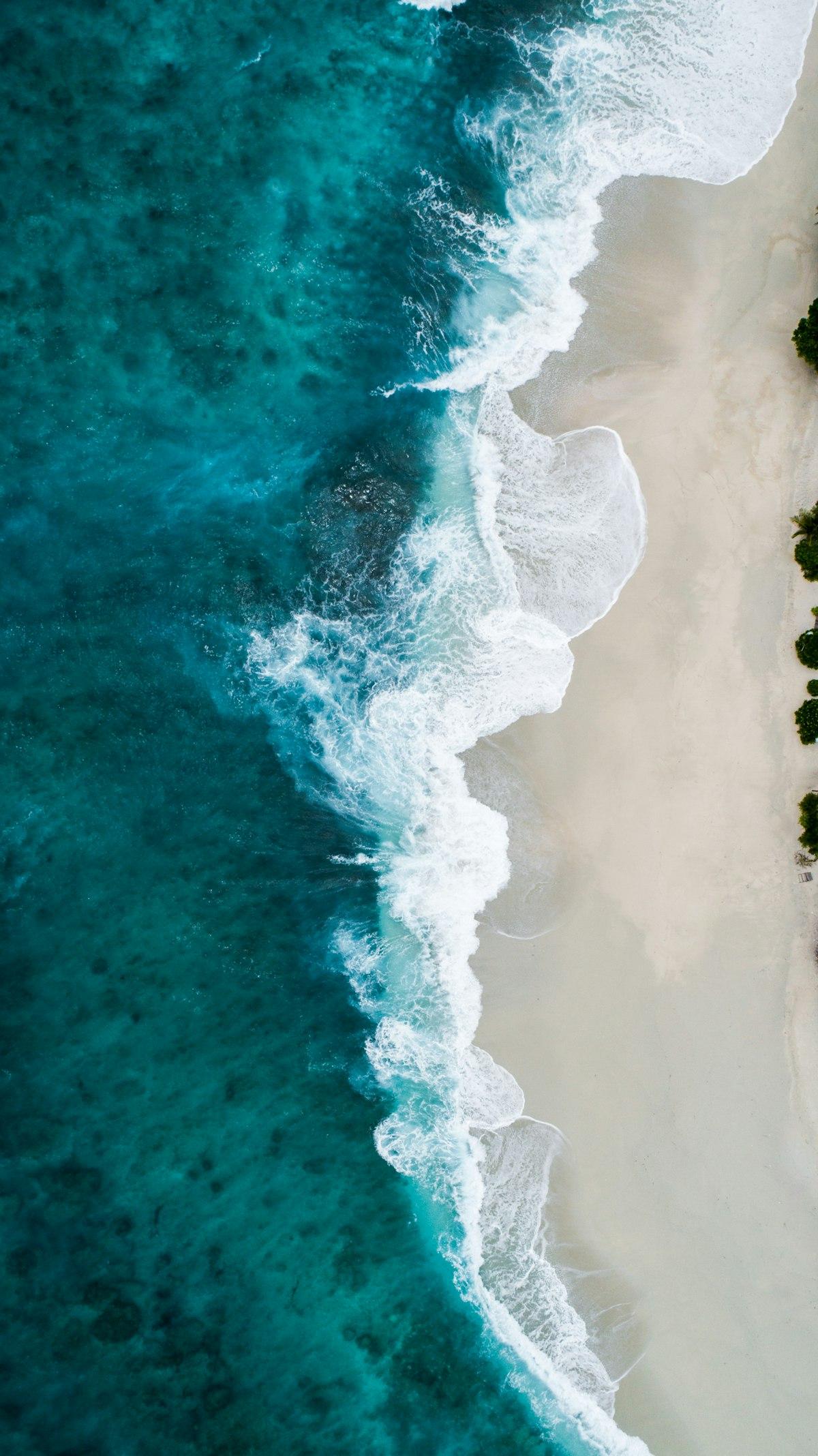 Turquoise water breaking over a rocky coastline from above