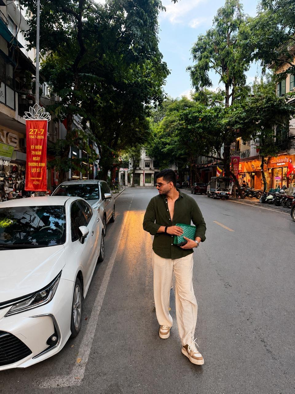Akshat walking down a tree-lined street in Hanoi in the late afternoon