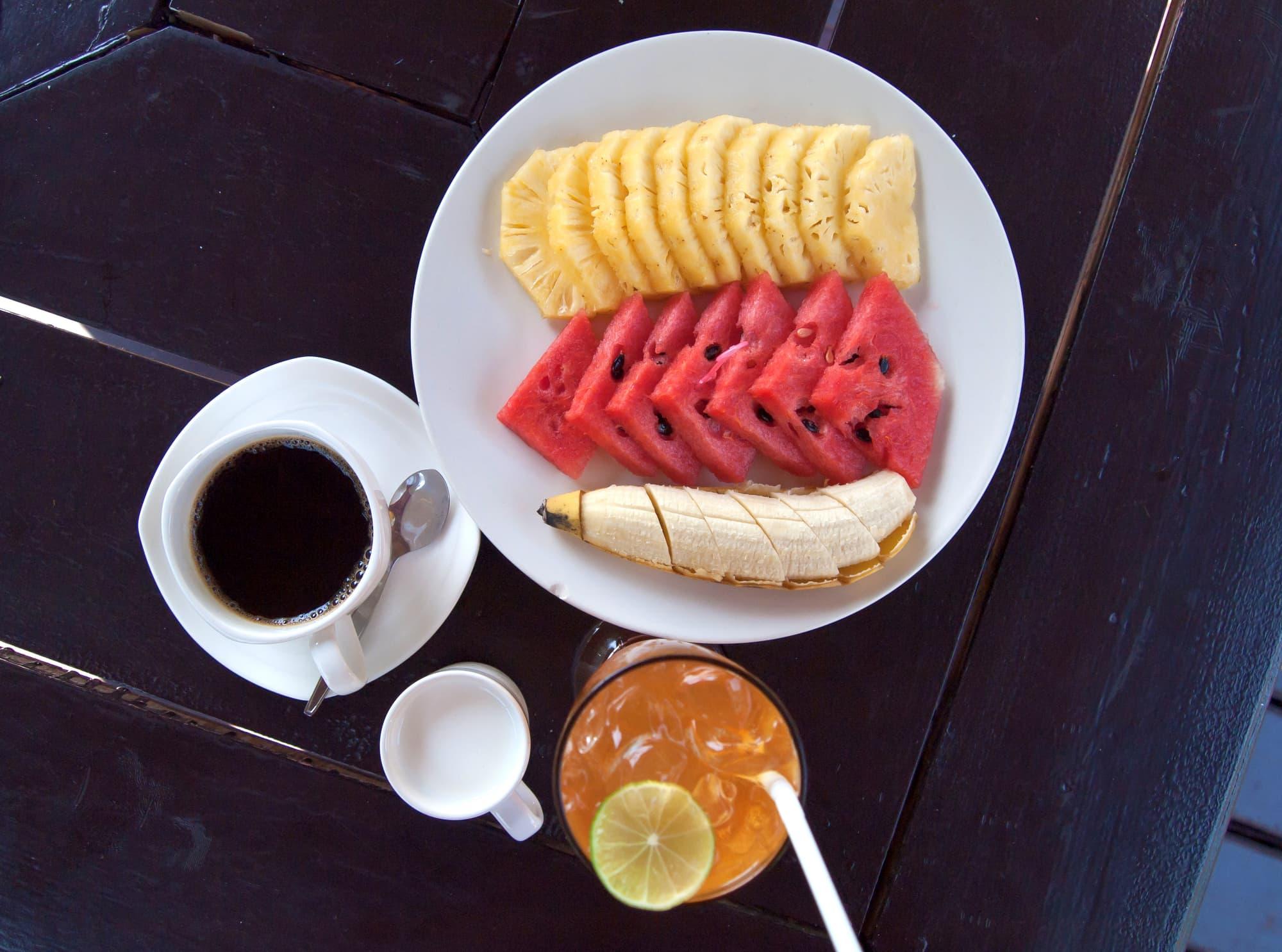 A tropical breakfast: fruit, coffee and juice on a wooden table