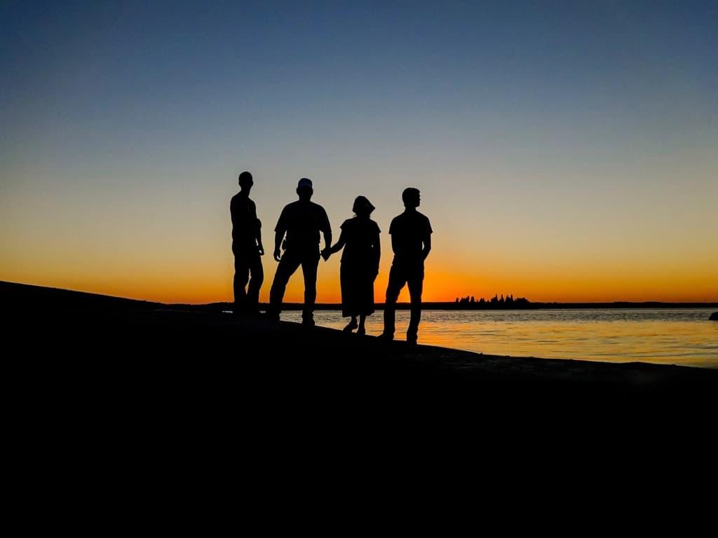 Four friends silhouetted on a hill at dusk