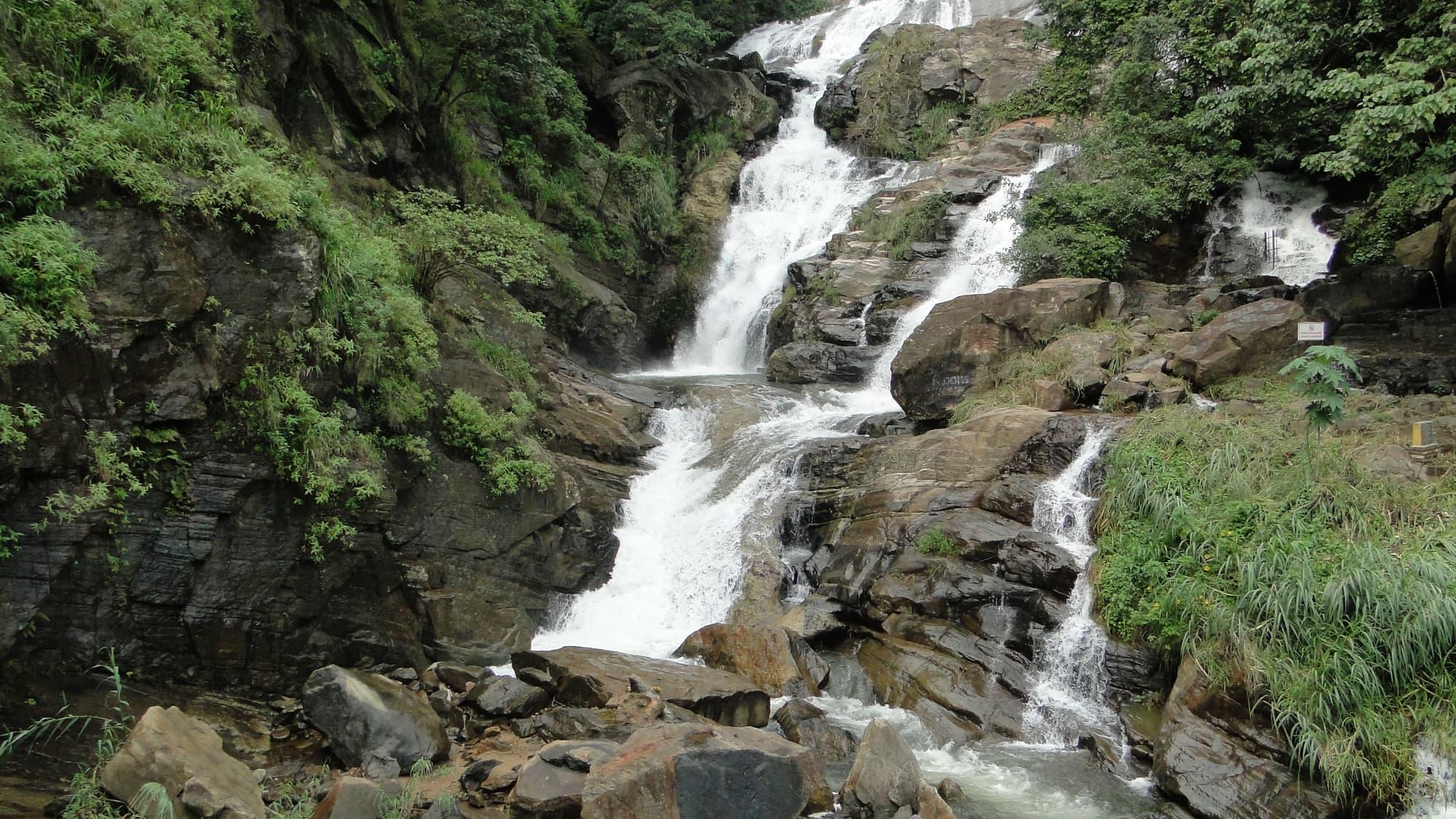 A waterfall tumbling over rock shelves into a jungle gorge