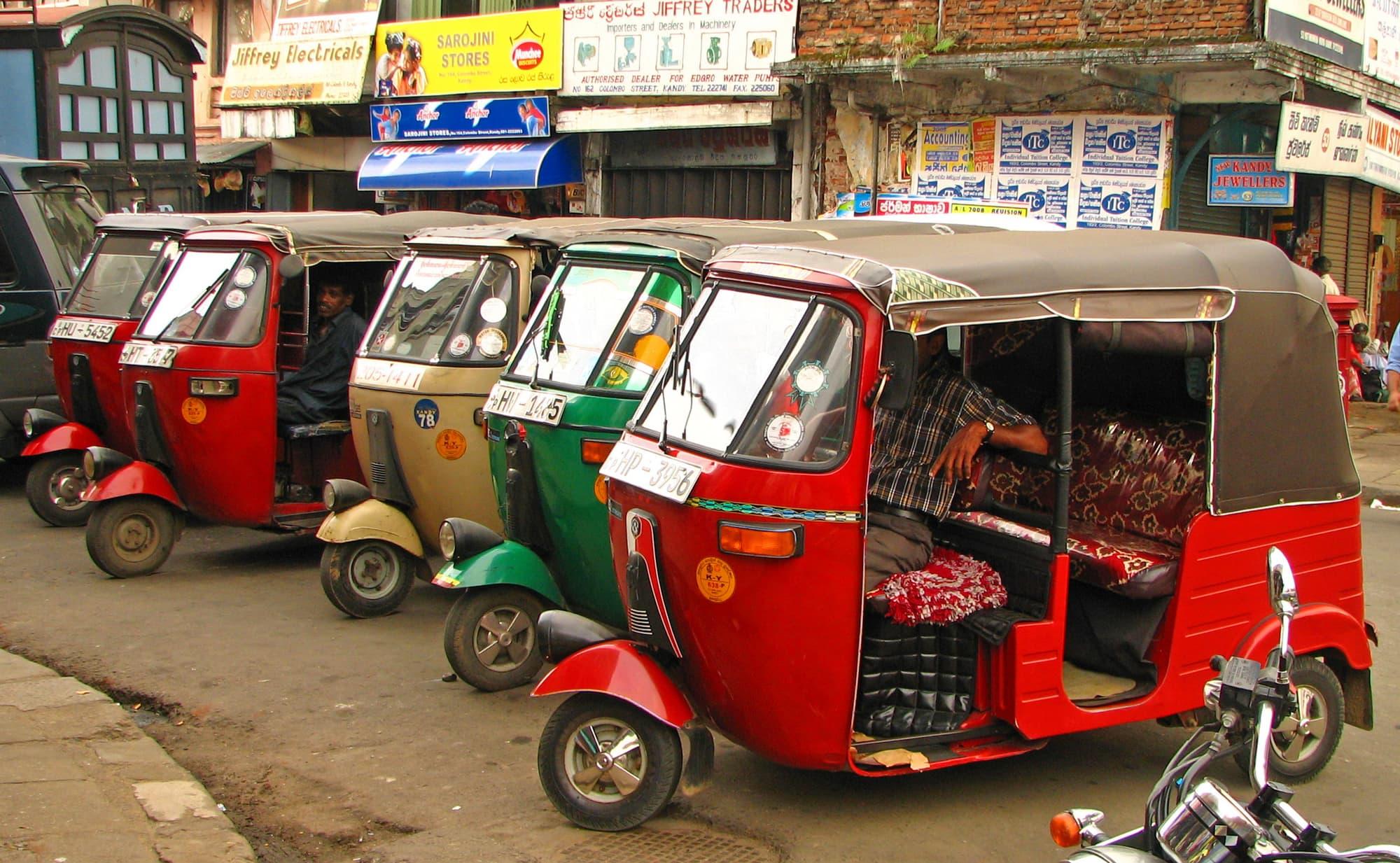 Tuk-tuks lined up waiting for fares on a busy street