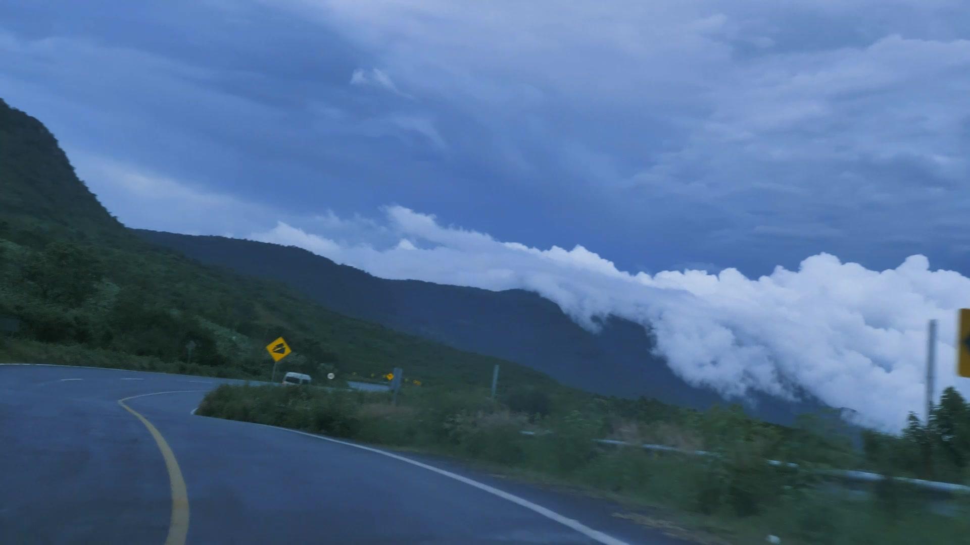 A road curving through green mountains under low cloud