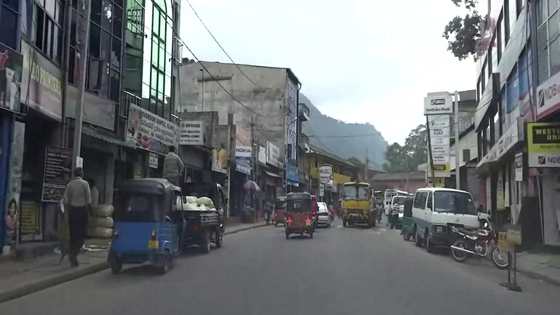 Driving down a busy town street full of tuk-tuks and buses