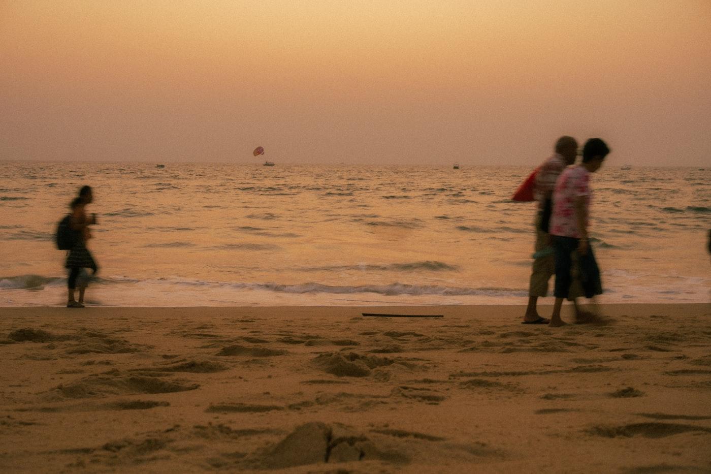 People walking along a beach in warm hazy light