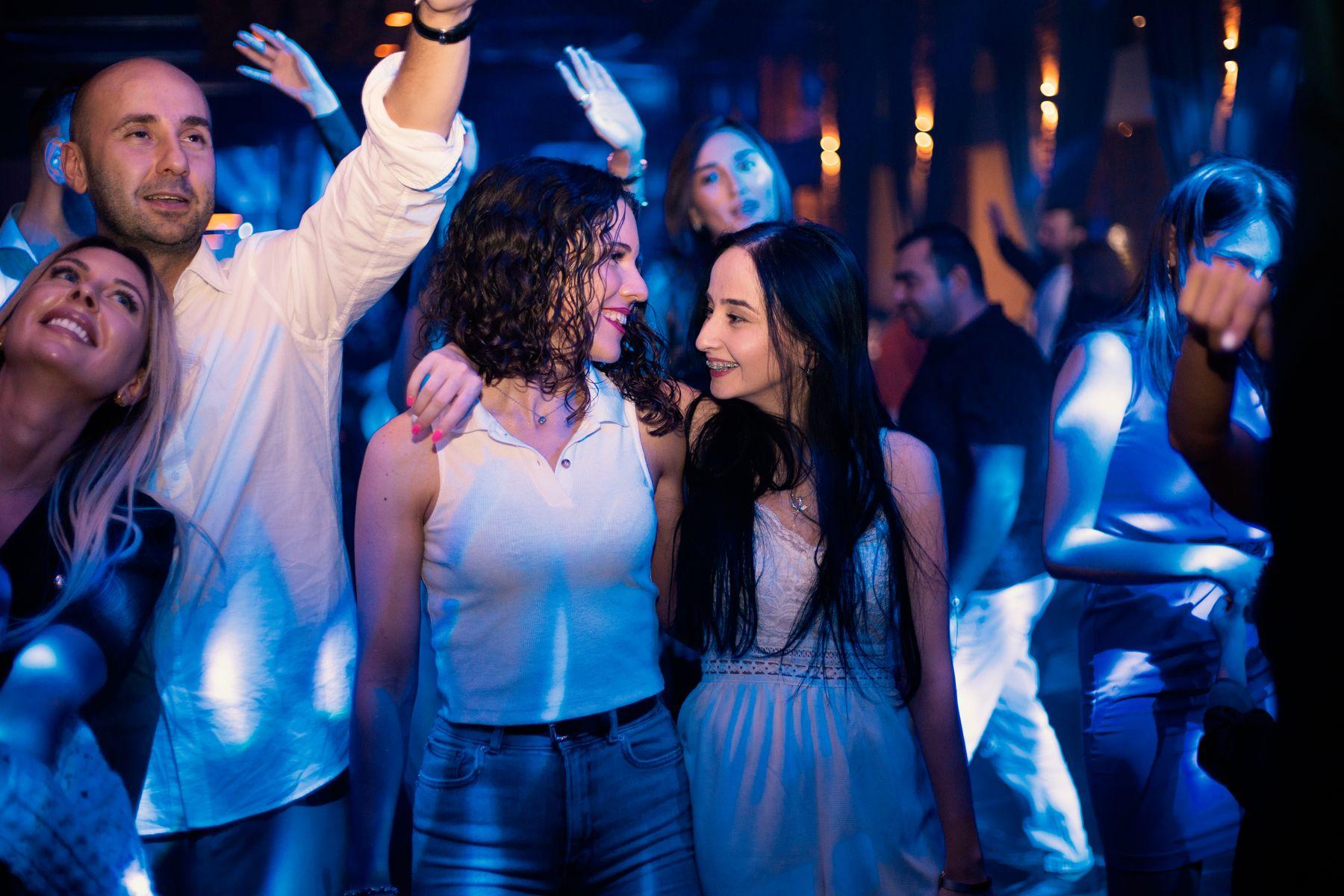 Friends dancing together in a crowded club under blue light