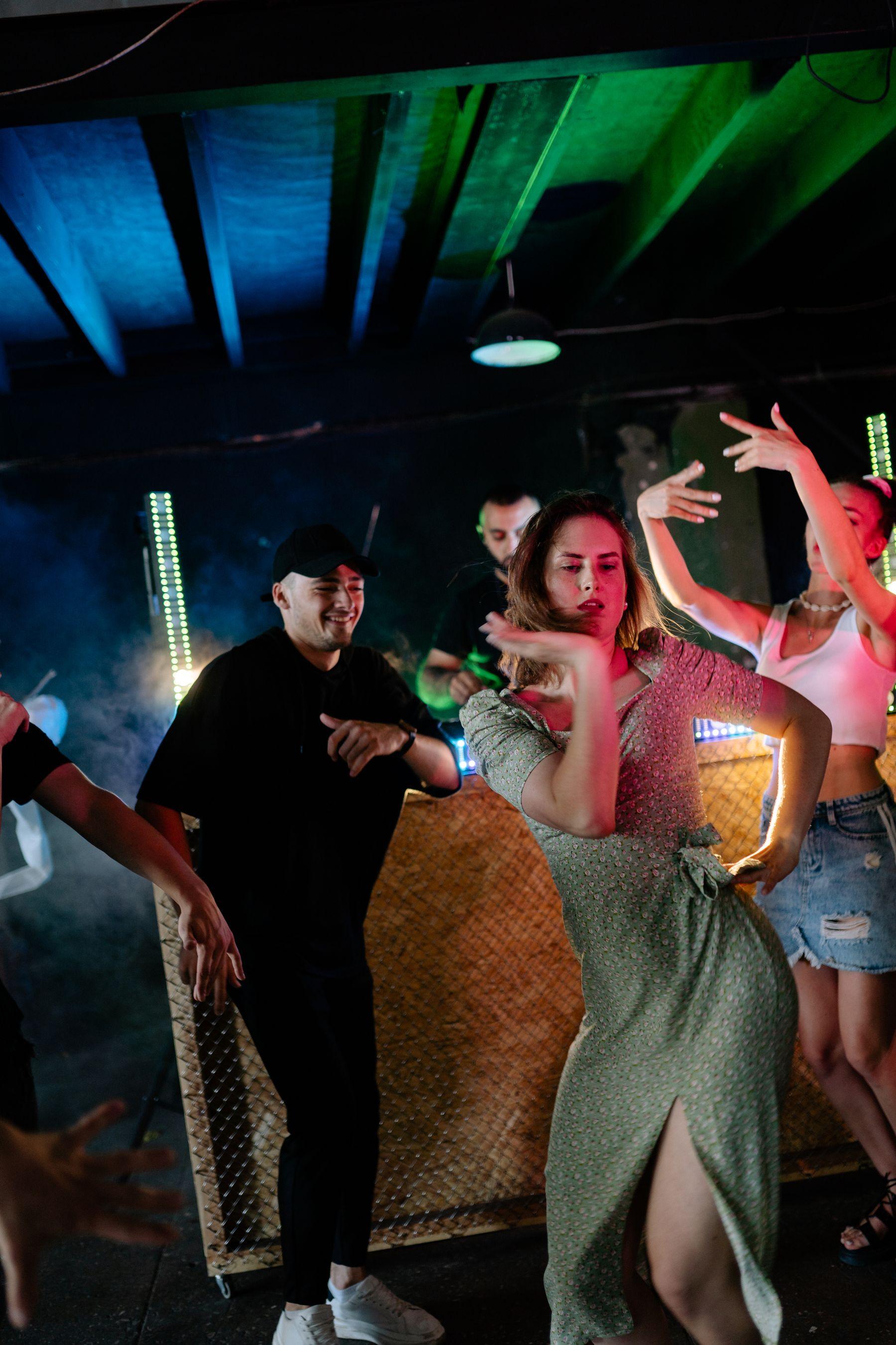 People mid-dance in a dark venue strung with coloured light